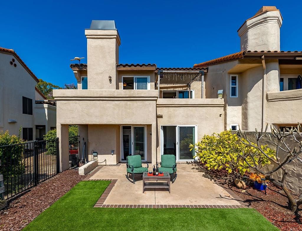 Back patio with turf yard, seating area, and balcony
